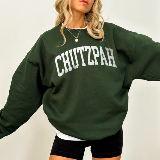 Person wearing a green sweatshirt with 'CHUTZPAH' text on a plain background