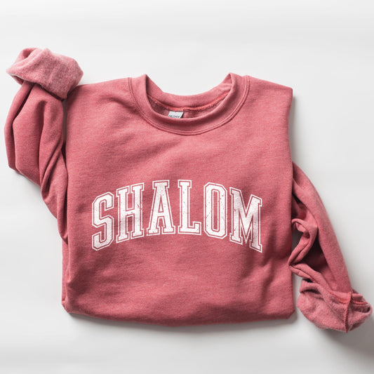 A red sweatshirt with the Hebrew word 'Shalom' written in white on the front.