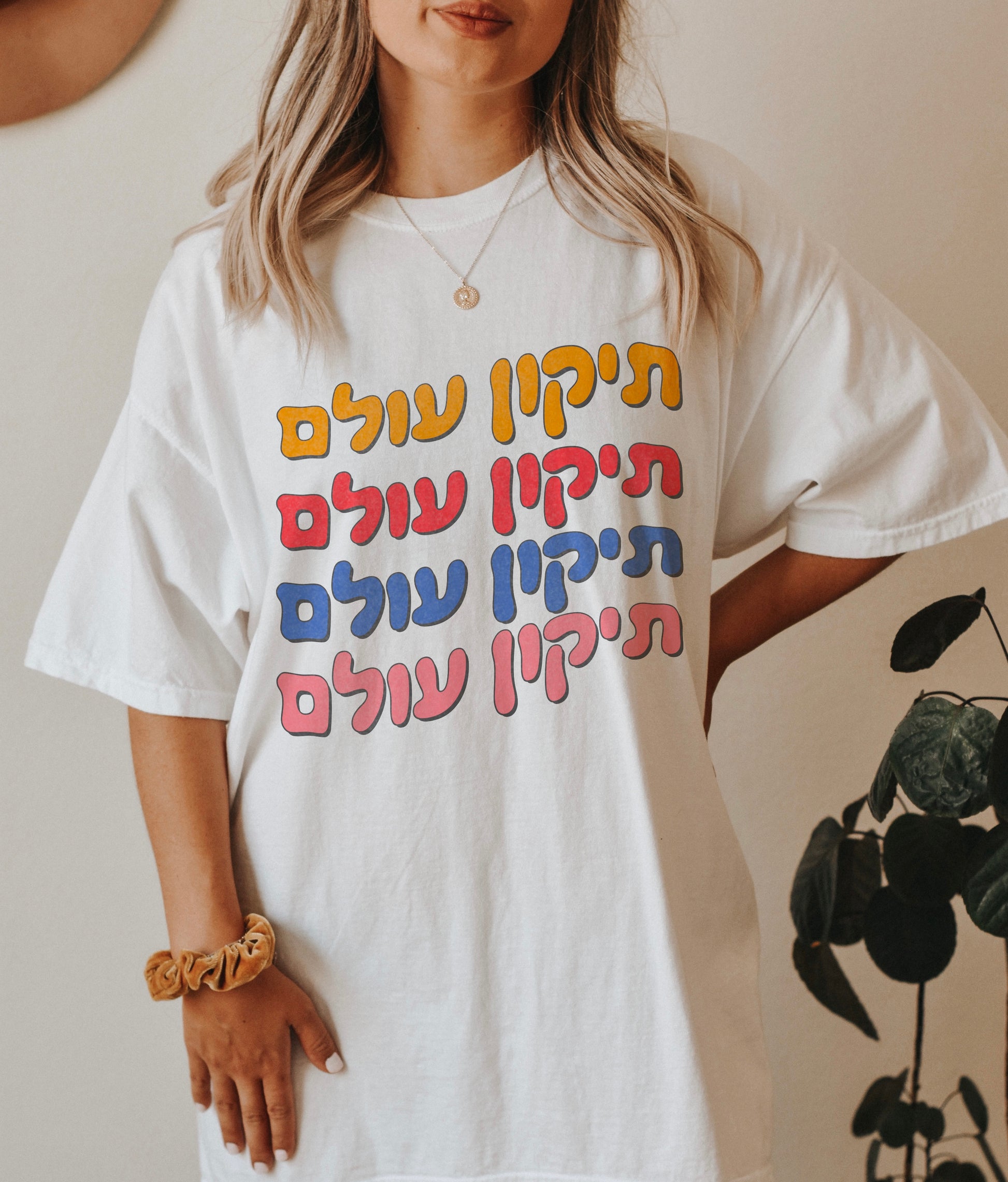 a woman standing in front of a plant wearing a white t - shirt